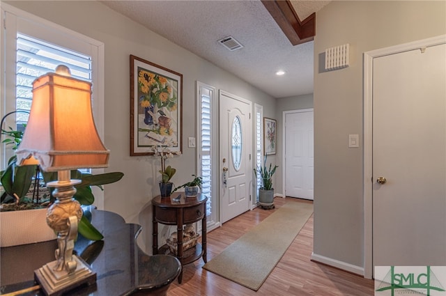 foyer entrance with a textured ceiling and light hardwood / wood-style flooring