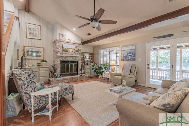 living room featuring a brick fireplace, vaulted ceiling with beams, a wealth of natural light, and light hardwood / wood-style floors