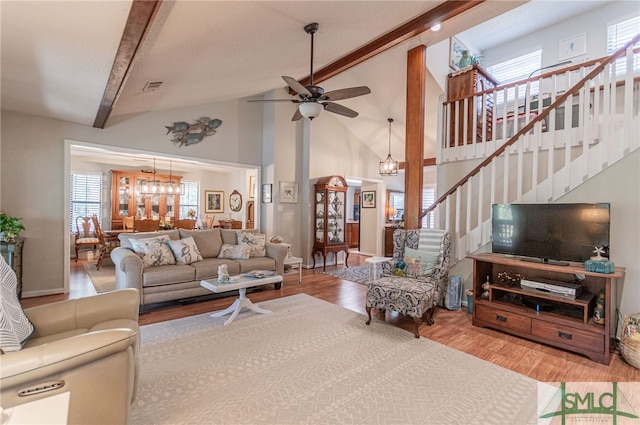 living room with beamed ceiling, ceiling fan with notable chandelier, high vaulted ceiling, and light hardwood / wood-style flooring