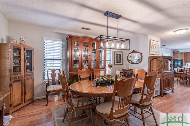 dining room with a textured ceiling and light hardwood / wood-style flooring