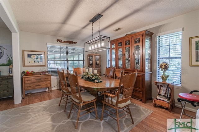 dining area with plenty of natural light, a textured ceiling, and light wood-type flooring