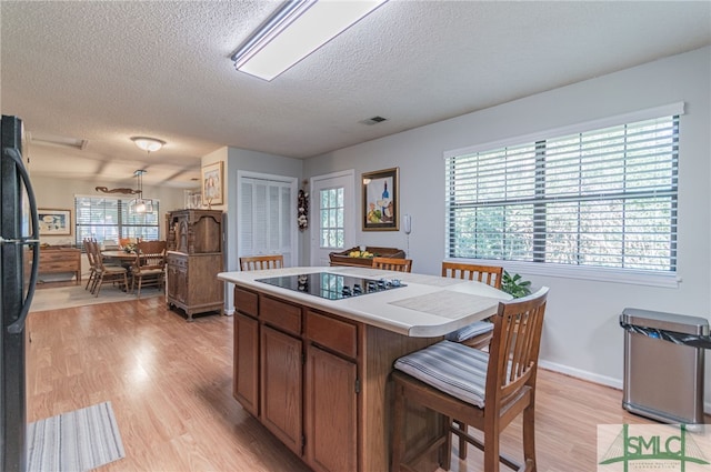 kitchen featuring a center island, light hardwood / wood-style floors, a textured ceiling, and black appliances