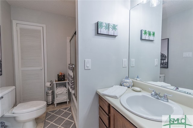 bathroom featuring vanity, tile patterned flooring, toilet, and a textured ceiling