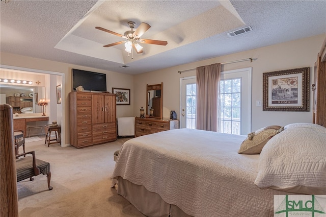 bedroom with connected bathroom, access to outside, a raised ceiling, light carpet, and a textured ceiling