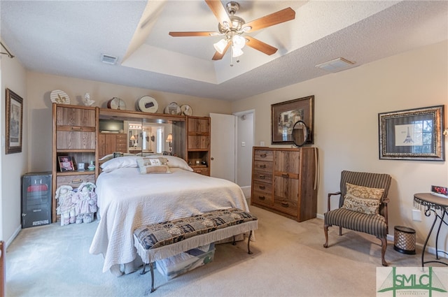 carpeted bedroom with a textured ceiling and a tray ceiling