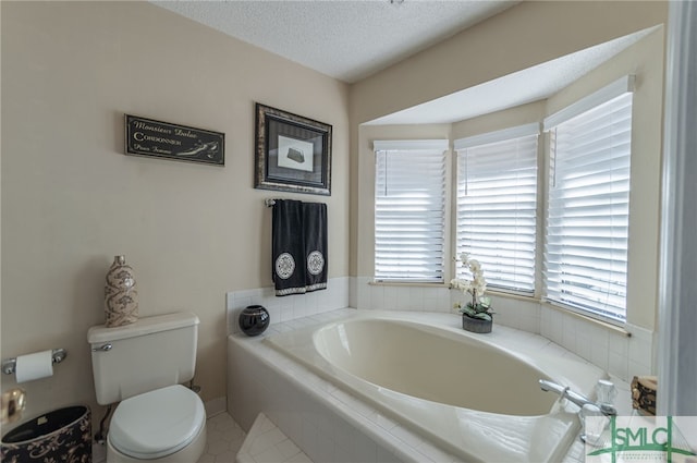 bathroom featuring a relaxing tiled tub, a textured ceiling, and toilet