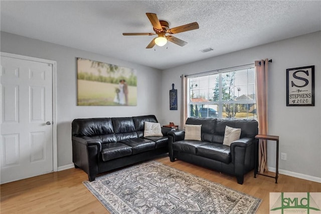 living room with hardwood / wood-style floors, a textured ceiling, and ceiling fan