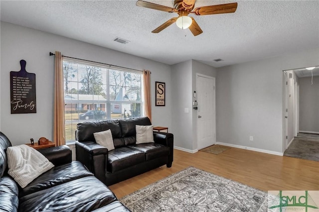 living room featuring ceiling fan, a textured ceiling, and light wood-type flooring