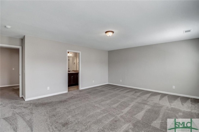 unfurnished bedroom featuring ensuite bathroom and carpet