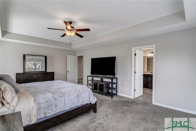 bedroom featuring carpet floors, a raised ceiling, ceiling fan, and ensuite bathroom