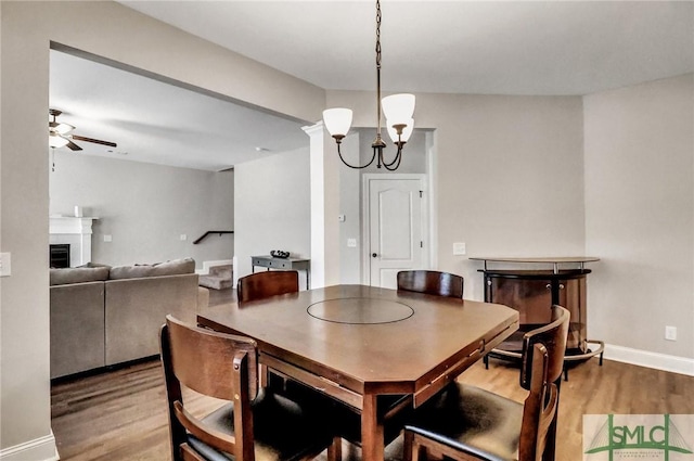 dining area with ceiling fan with notable chandelier and hardwood / wood-style floors