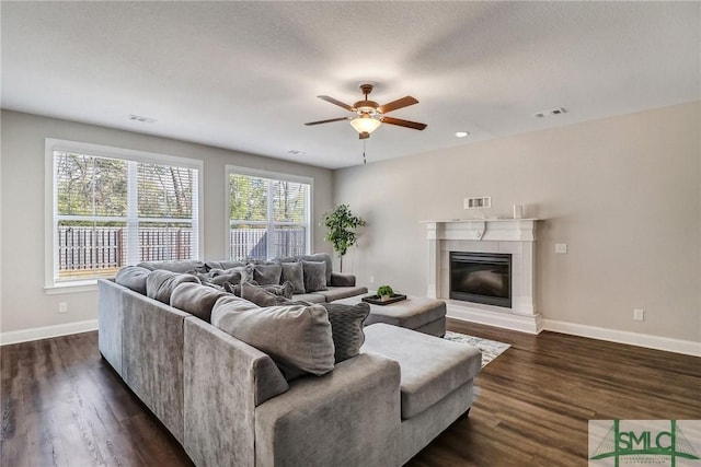 living room featuring a textured ceiling, a fireplace, dark hardwood / wood-style floors, and ceiling fan