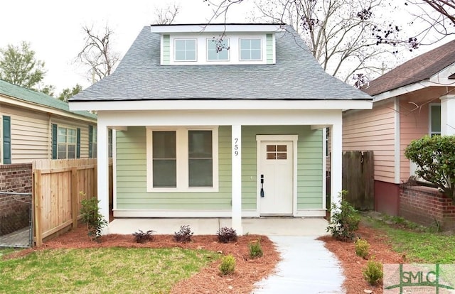 bungalow-style home featuring roof with shingles and fence