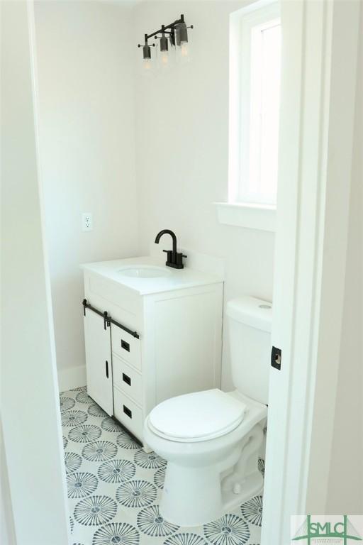 bathroom featuring toilet, tile patterned flooring, vanity, and baseboards