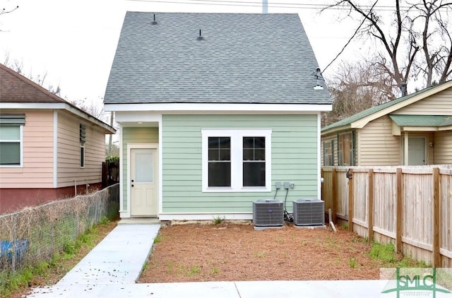 back of house featuring a fenced backyard, a shingled roof, and central AC