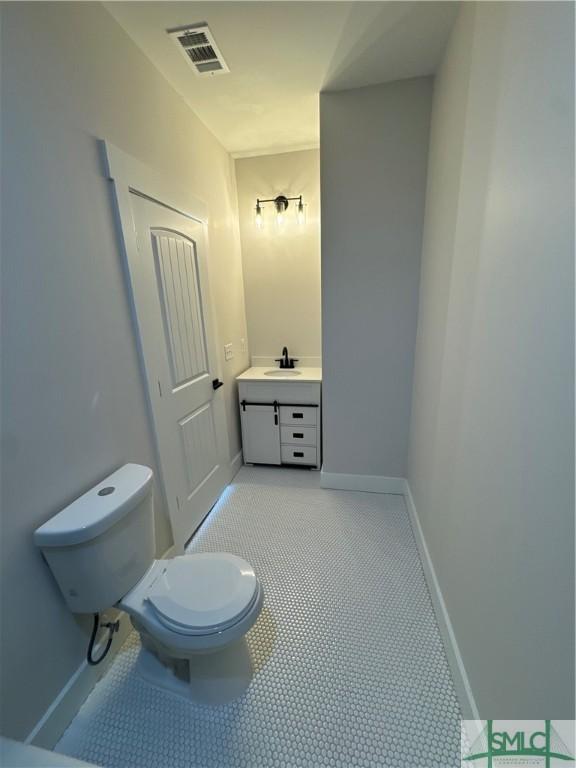 bathroom with toilet, vanity, visible vents, and baseboards