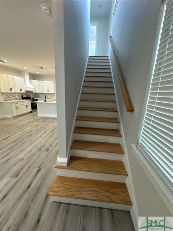 staircase with baseboards and wood finished floors