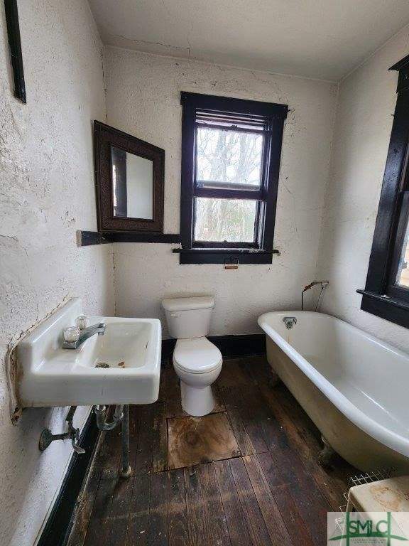 bathroom featuring a washtub, sink, hardwood / wood-style flooring, and toilet