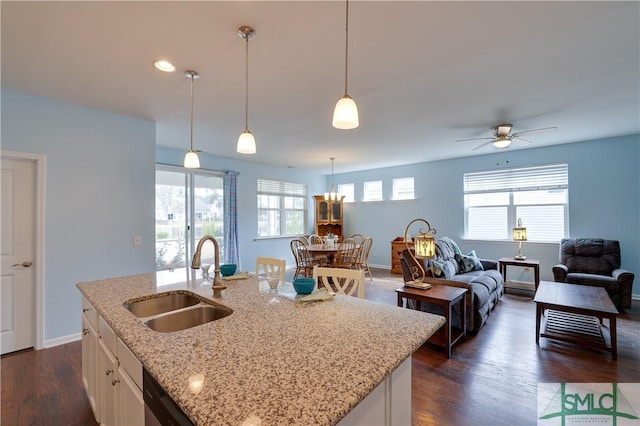 kitchen with pendant lighting, sink, white cabinets, and a center island with sink