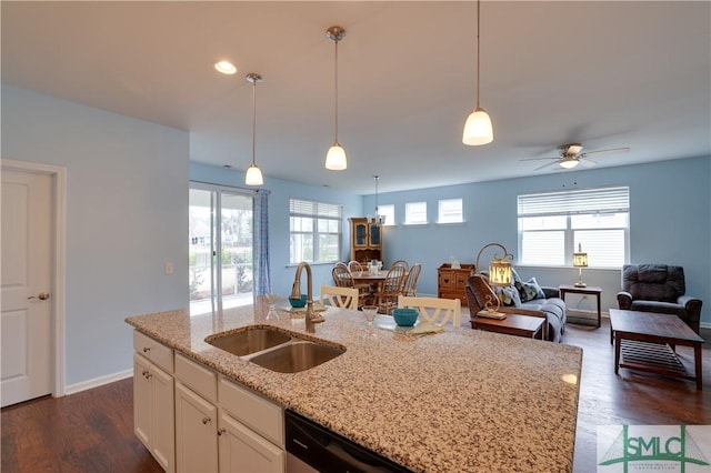 kitchen featuring sink, white cabinetry, a kitchen island with sink, hanging light fixtures, and light stone counters