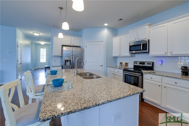 kitchen with stainless steel appliances, a breakfast bar area, sink, and a center island with sink