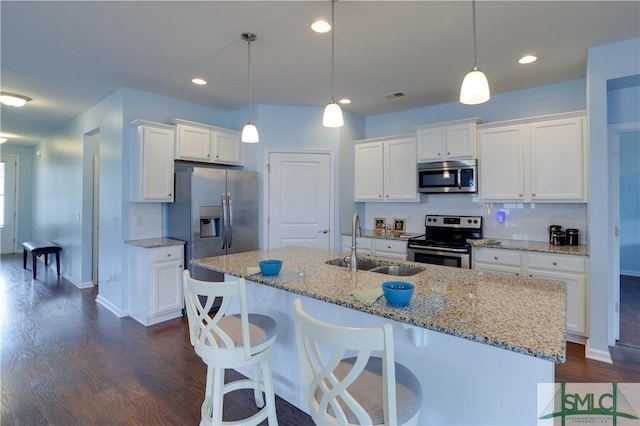 kitchen featuring pendant lighting, sink, appliances with stainless steel finishes, white cabinetry, and a kitchen island with sink