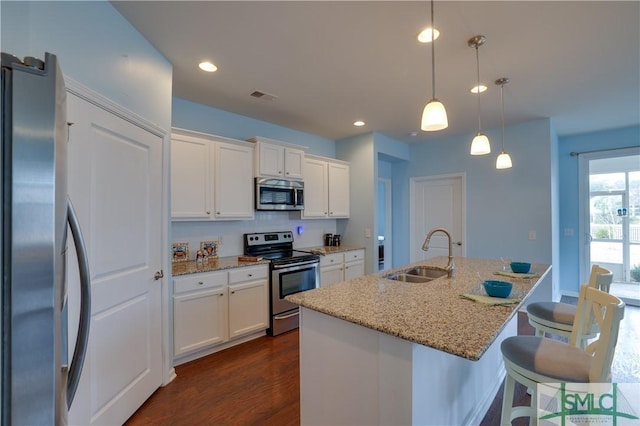 kitchen featuring sink, light stone counters, a center island with sink, pendant lighting, and stainless steel appliances