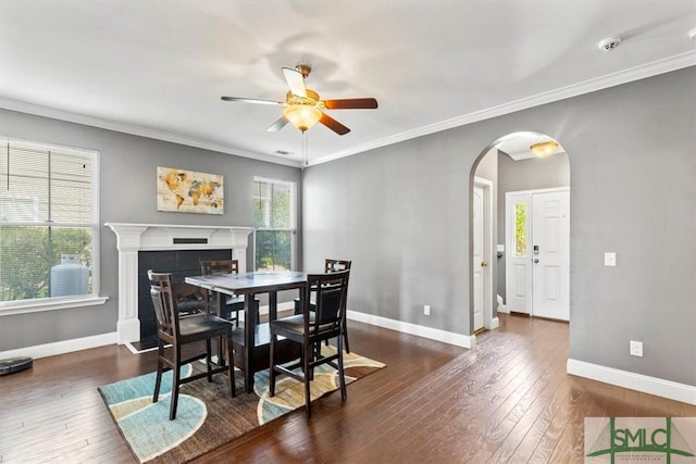 dining space with ceiling fan, ornamental molding, dark hardwood / wood-style flooring, and a tile fireplace