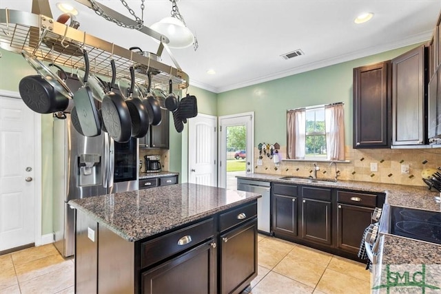 kitchen with appliances with stainless steel finishes, a center island, sink, and decorative backsplash