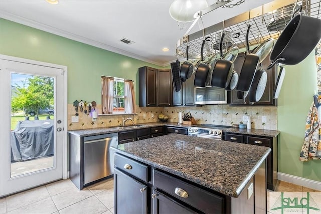 kitchen with tasteful backsplash, stainless steel appliances, sink, and a kitchen island