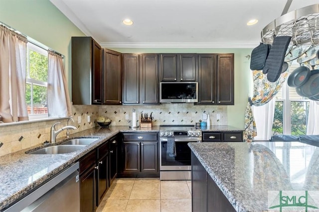 kitchen with sink, decorative backsplash, dark brown cabinetry, stainless steel appliances, and light stone countertops