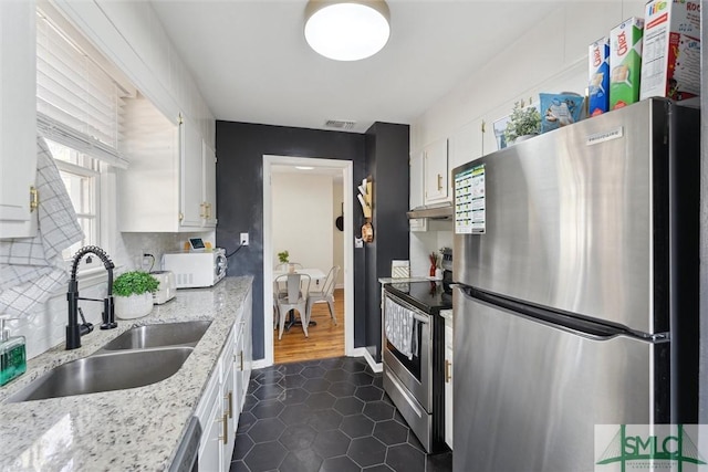 kitchen featuring sink, white cabinetry, stainless steel appliances, light stone countertops, and decorative backsplash