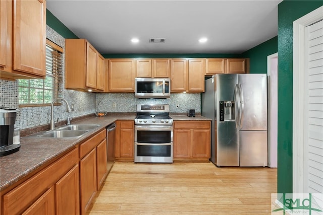 kitchen featuring stainless steel appliances, light hardwood / wood-style floors, sink, and backsplash