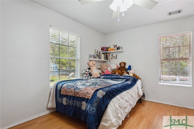bedroom with multiple windows, wood-type flooring, and ceiling fan