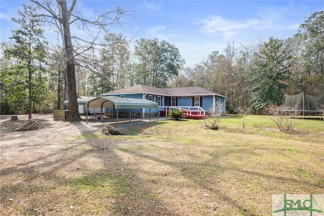 view of front facade with a carport, a trampoline, and a front yard