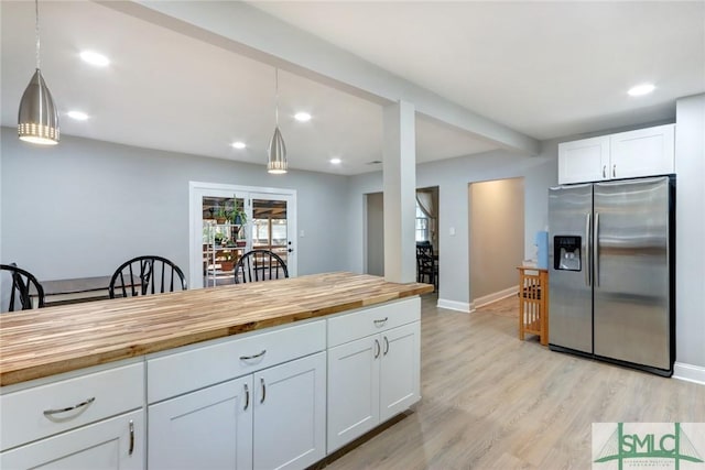 kitchen with pendant lighting, butcher block counters, white cabinetry, stainless steel refrigerator with ice dispenser, and light wood-type flooring