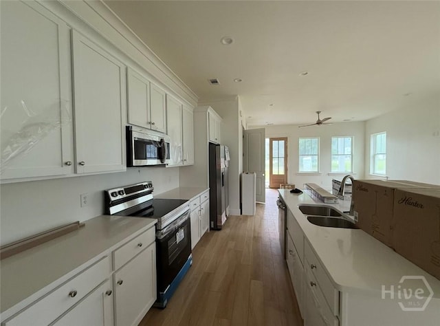 511 Goodman Dr, Midway, GA 31320 - kitchen featuring appliances with stainless steel finishes, a sink, wood finished floors, white cabinetry, and light countertops