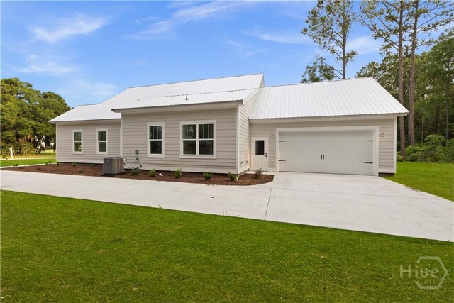 511 Goodman Dr, Midway, GA 31320 - view of front facade with cooling unit, driveway, a garage, a front yard, and metal roof