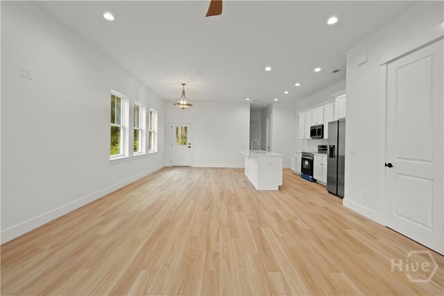 511 Goodman Dr, Midway, GA 31320 - unfurnished living room with light wood-type flooring, recessed lighting, baseboards, a chandelier, and a sink
