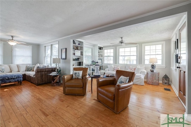 115 2nd Ave, Tybee Island, GA 31328 - living area featuring a textured ceiling, ornamental molding, a ceiling fan, light wood-style floors, and healthy amount of natural light