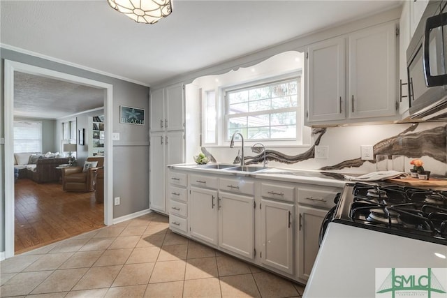 115 2nd Ave, Tybee Island, GA 31328 - kitchen with light tile patterned floors, light countertops, ornamental molding, and white cabinetry