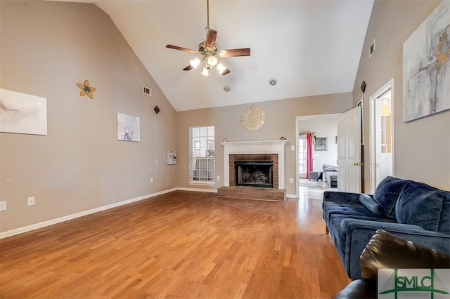 living room featuring ceiling fan, a brick fireplace, high vaulted ceiling, and light wood-type flooring