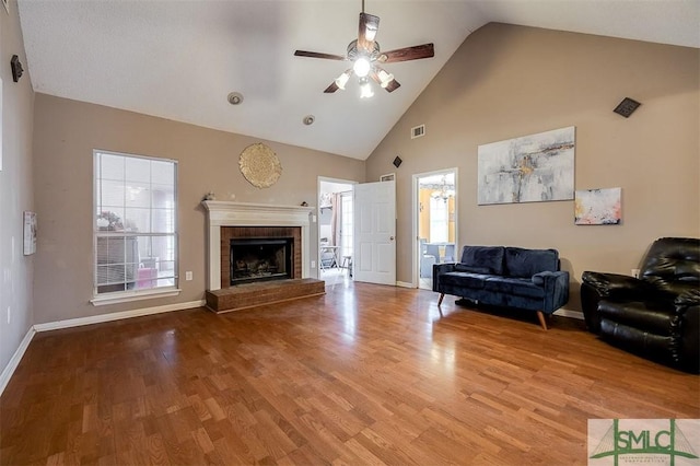 living room featuring hardwood / wood-style flooring, ceiling fan, high vaulted ceiling, and a brick fireplace