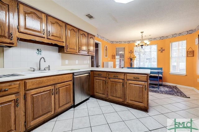 kitchen with light tile patterned flooring, pendant lighting, stainless steel dishwasher, kitchen peninsula, and a textured ceiling