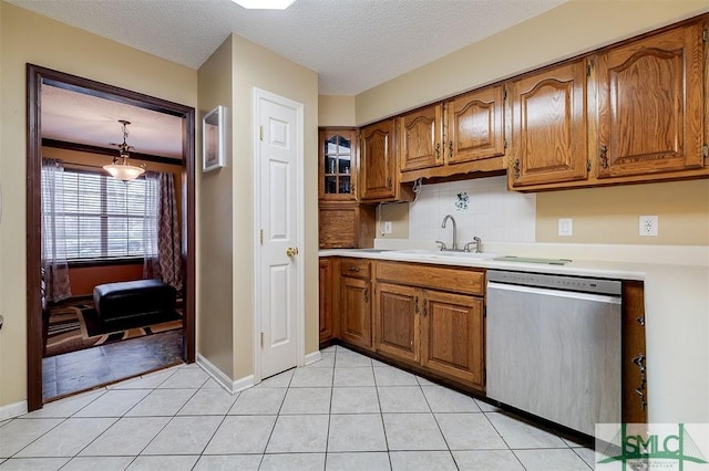 kitchen with sink, dishwasher, backsplash, a textured ceiling, and decorative light fixtures