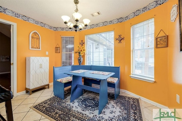 dining space with light tile patterned floors, a textured ceiling, and an inviting chandelier