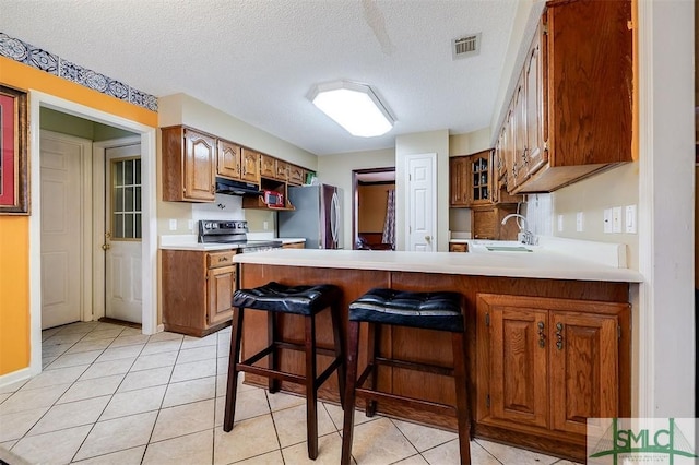 kitchen with stainless steel appliances, a kitchen bar, sink, and light tile patterned floors