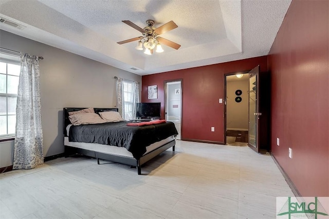 bedroom with a raised ceiling, ceiling fan, and a textured ceiling