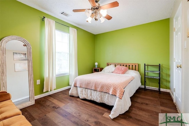 bedroom featuring ceiling fan, dark hardwood / wood-style floors, and a textured ceiling