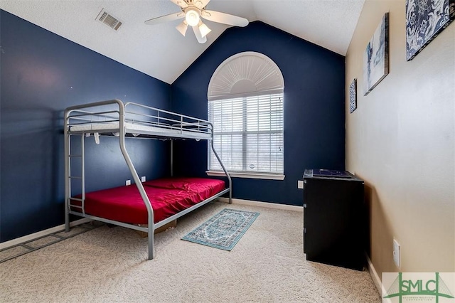 bedroom with vaulted ceiling, carpet floors, a textured ceiling, and ceiling fan